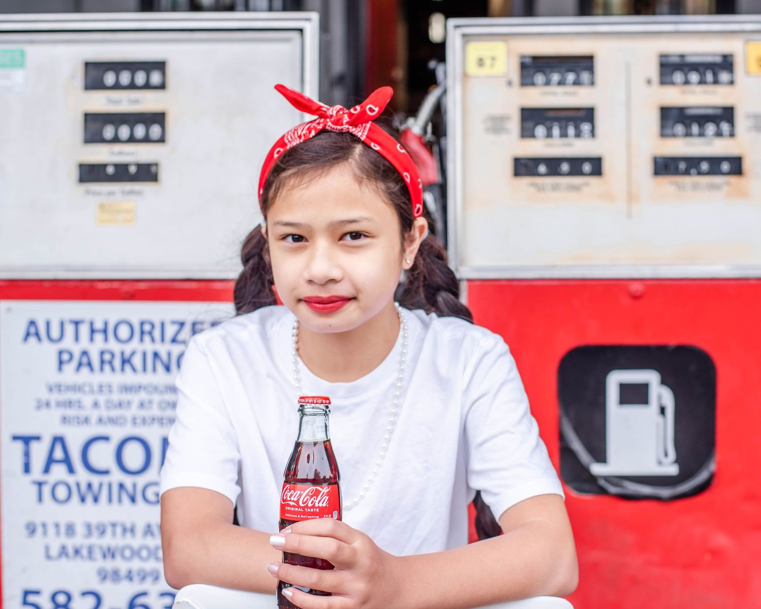 Person in white shirt with red bandana seated against red and white business signage.