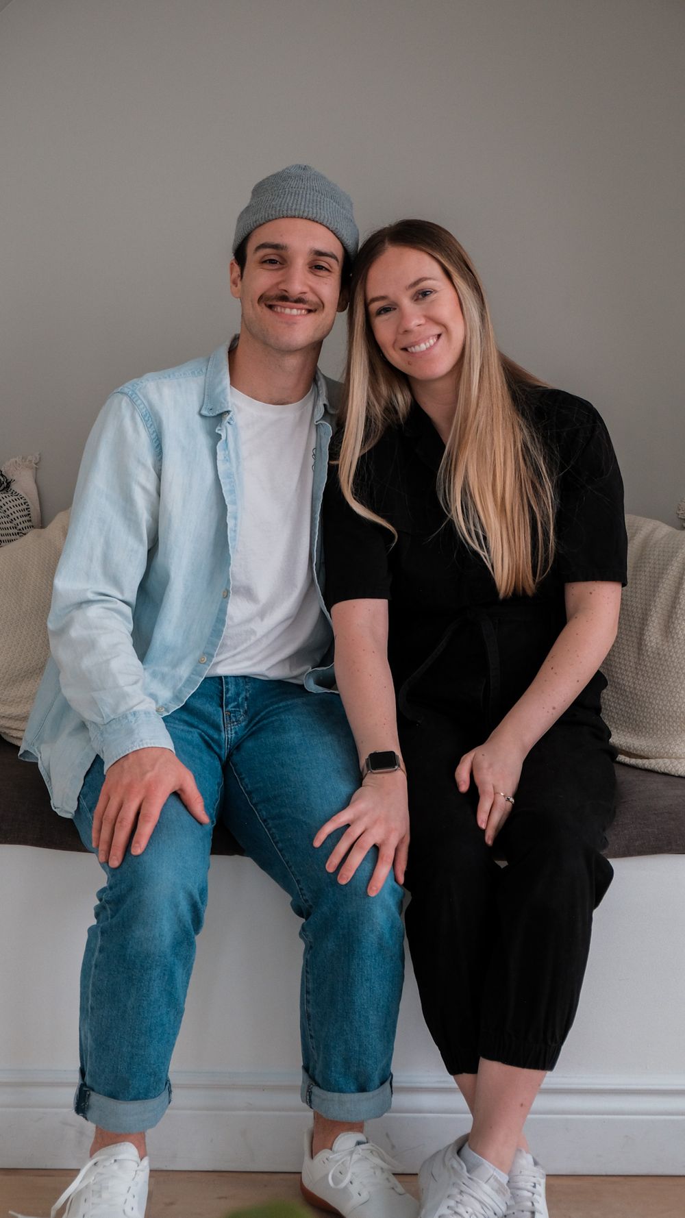 Couples photography with with wife and husband sitting upright, cuddling and smiling at the camera.