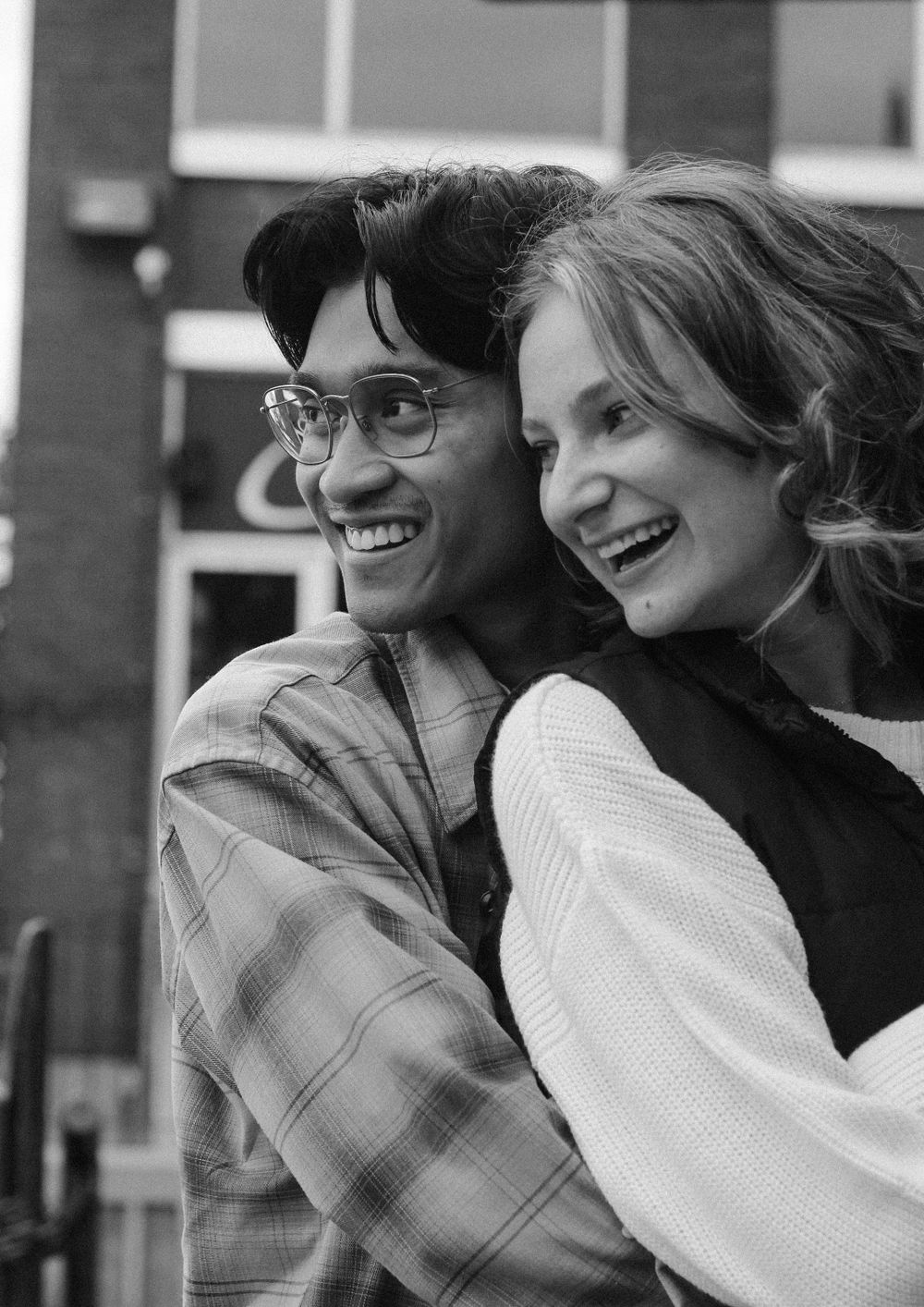 Couples photography with man holding woman from behind and both looking into the distance.