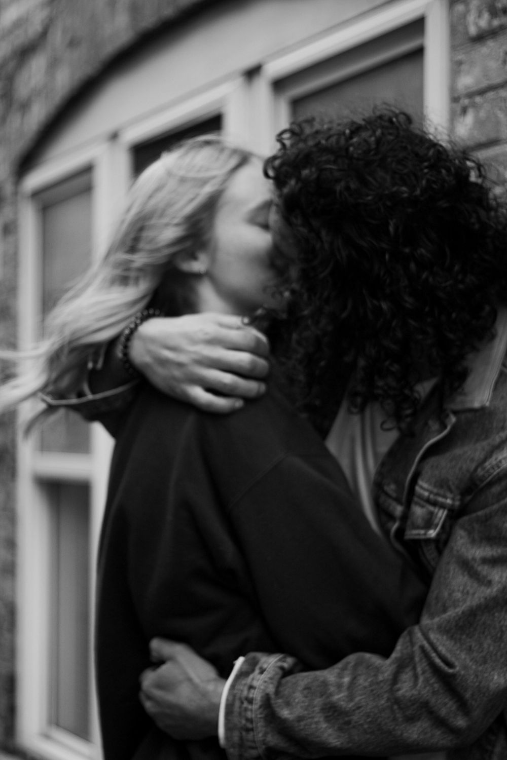 Couples photography of a man and woman kissing, with the man's arm around the woman's neck.