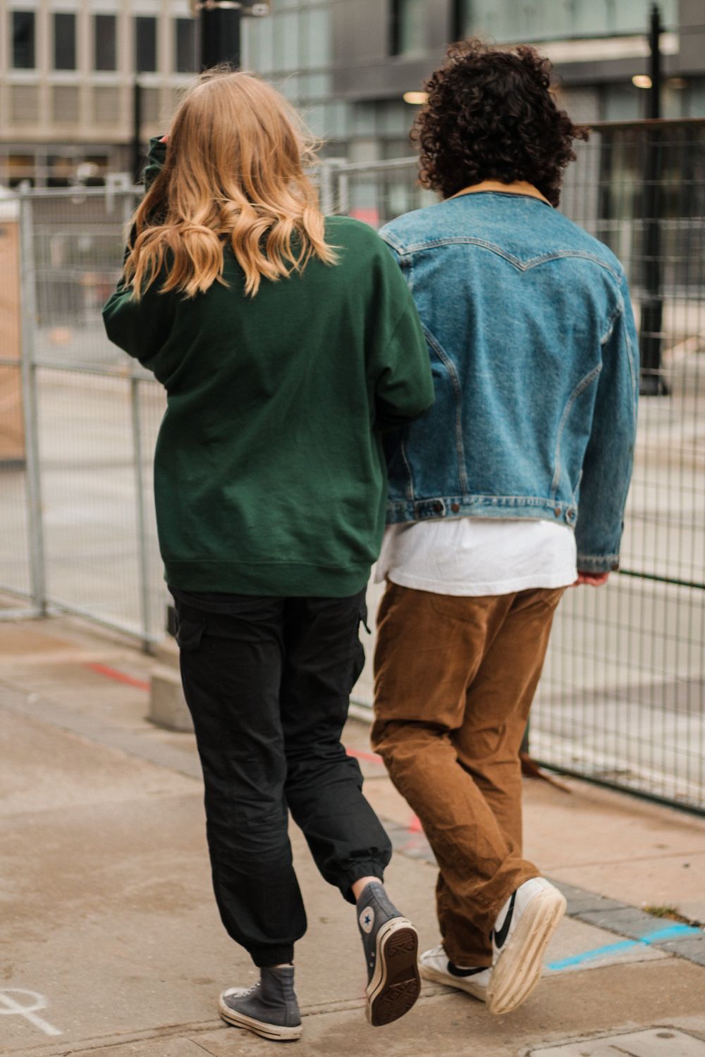 Couples photography with the man and woman holding arms walking down the sidewalk.