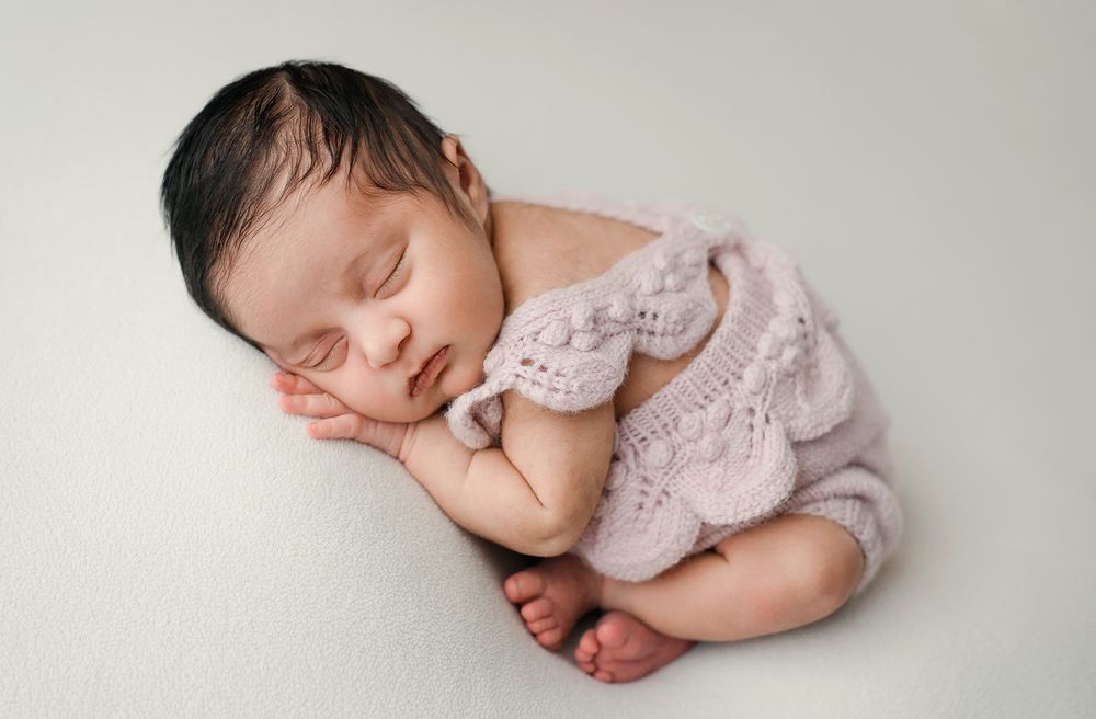 Newborn baby sleeping peacefully in soft pink outfit against white background in collage of four similar poses.