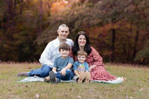 Family of four sits together on a blanket during an autumn photo session.