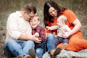 Family sharing tender moments together outdoors in casual clothing.