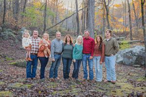 Large group poses on rocky terrain with autumn foliage in background.