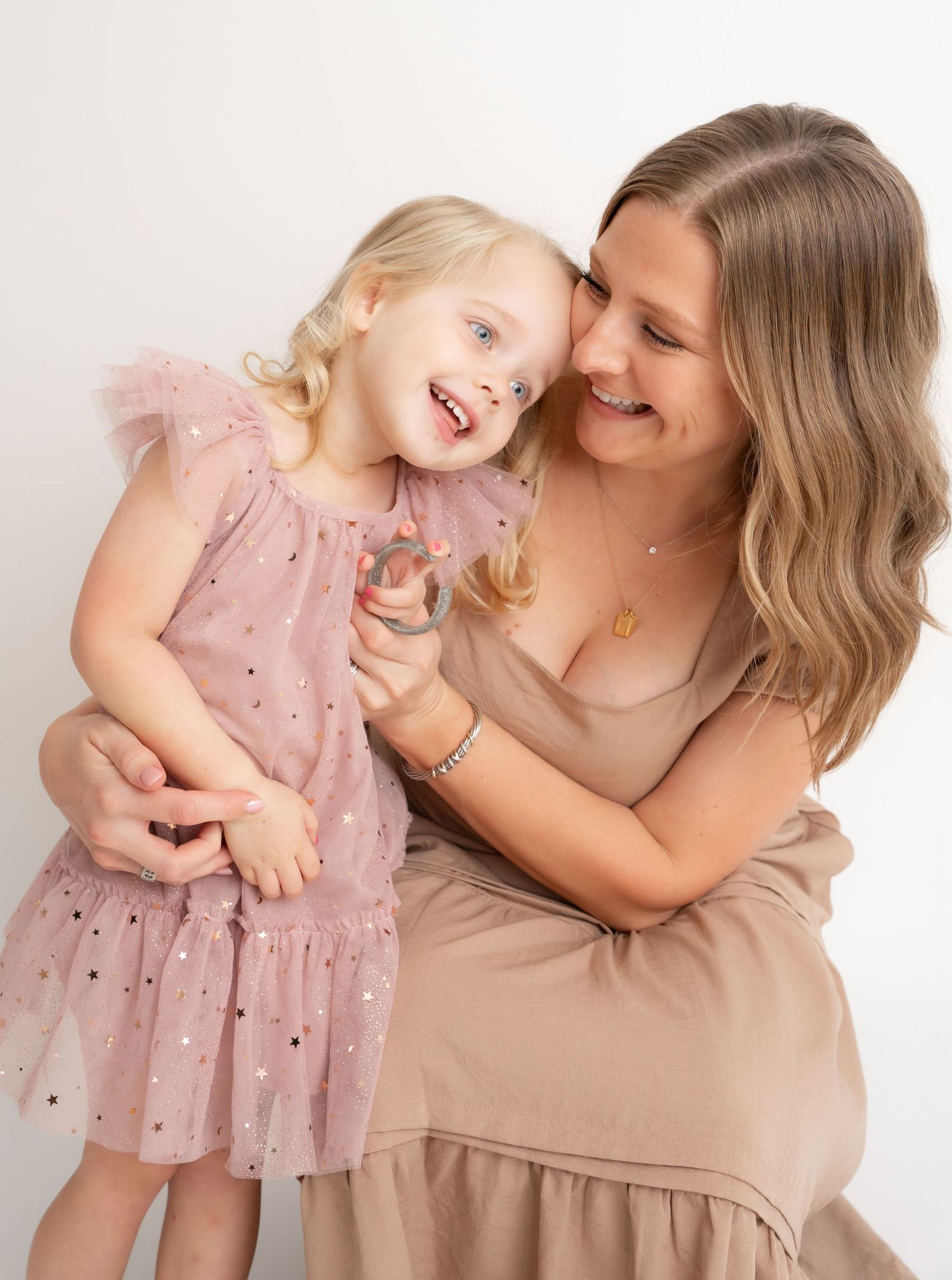 A tender moment captured between parent and child wearing coordinating pink and neutral tones.