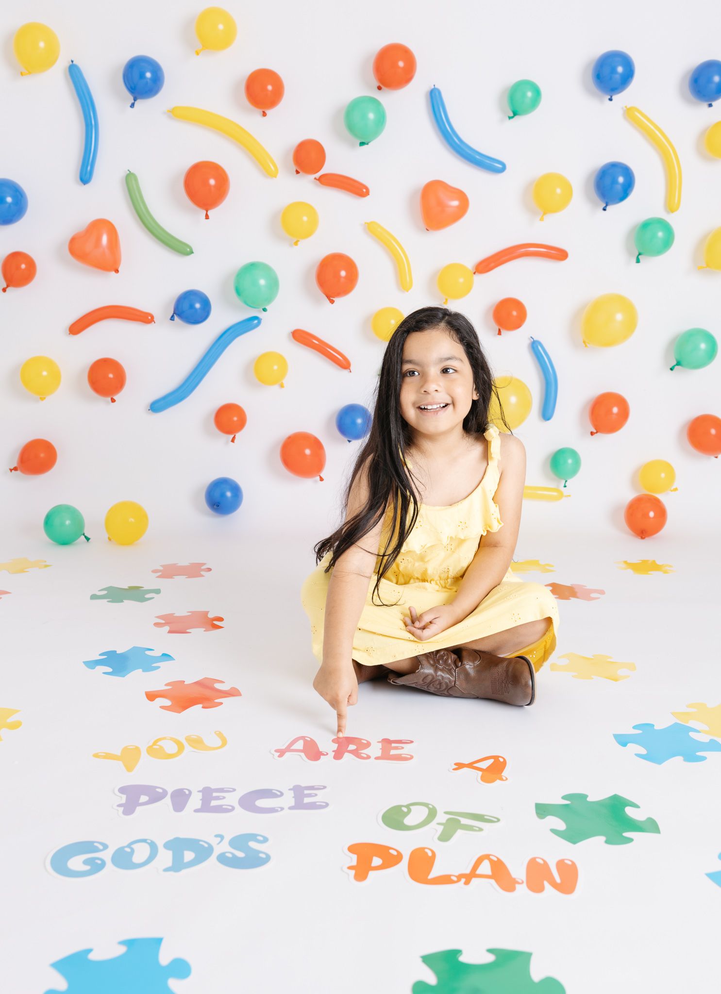 Colorful puzzle pieces and confetti create a vibrant playful background for a photo shoot.