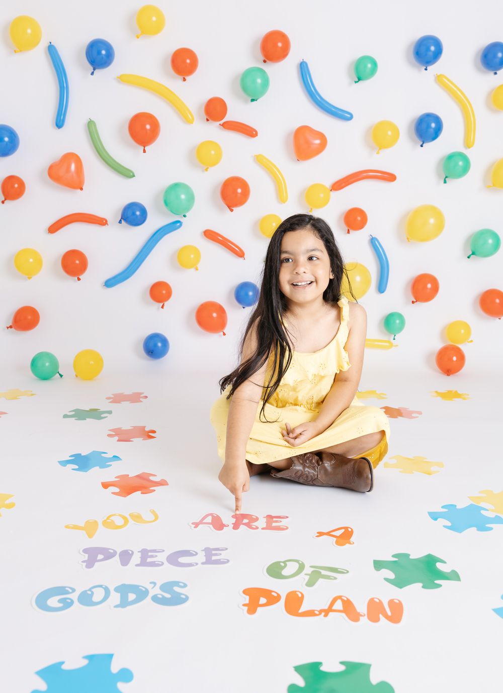 Colorful puzzle pieces and confetti create a vibrant playful background for a photo shoot.