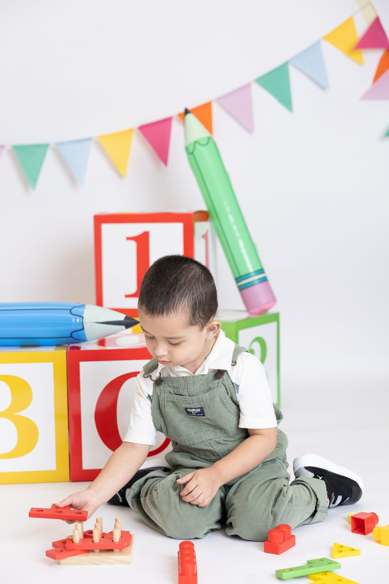 Child playing with educational toys and blocks under colorful party banner decorations.