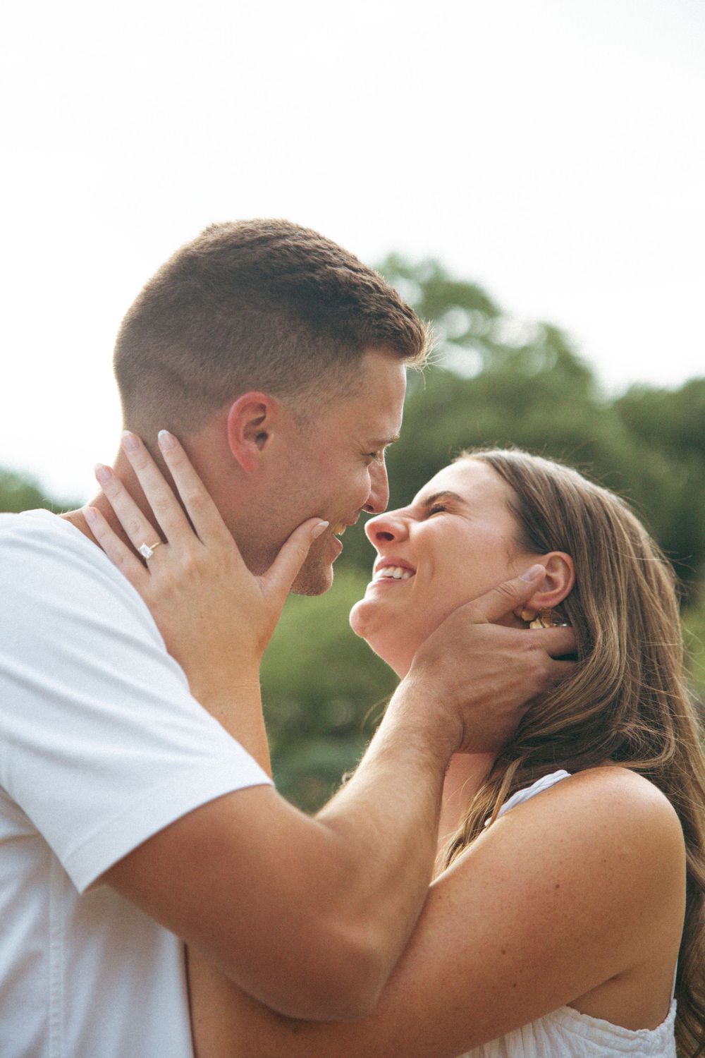 A couple shares an intimate close-up moment outdoors in natural lighting.