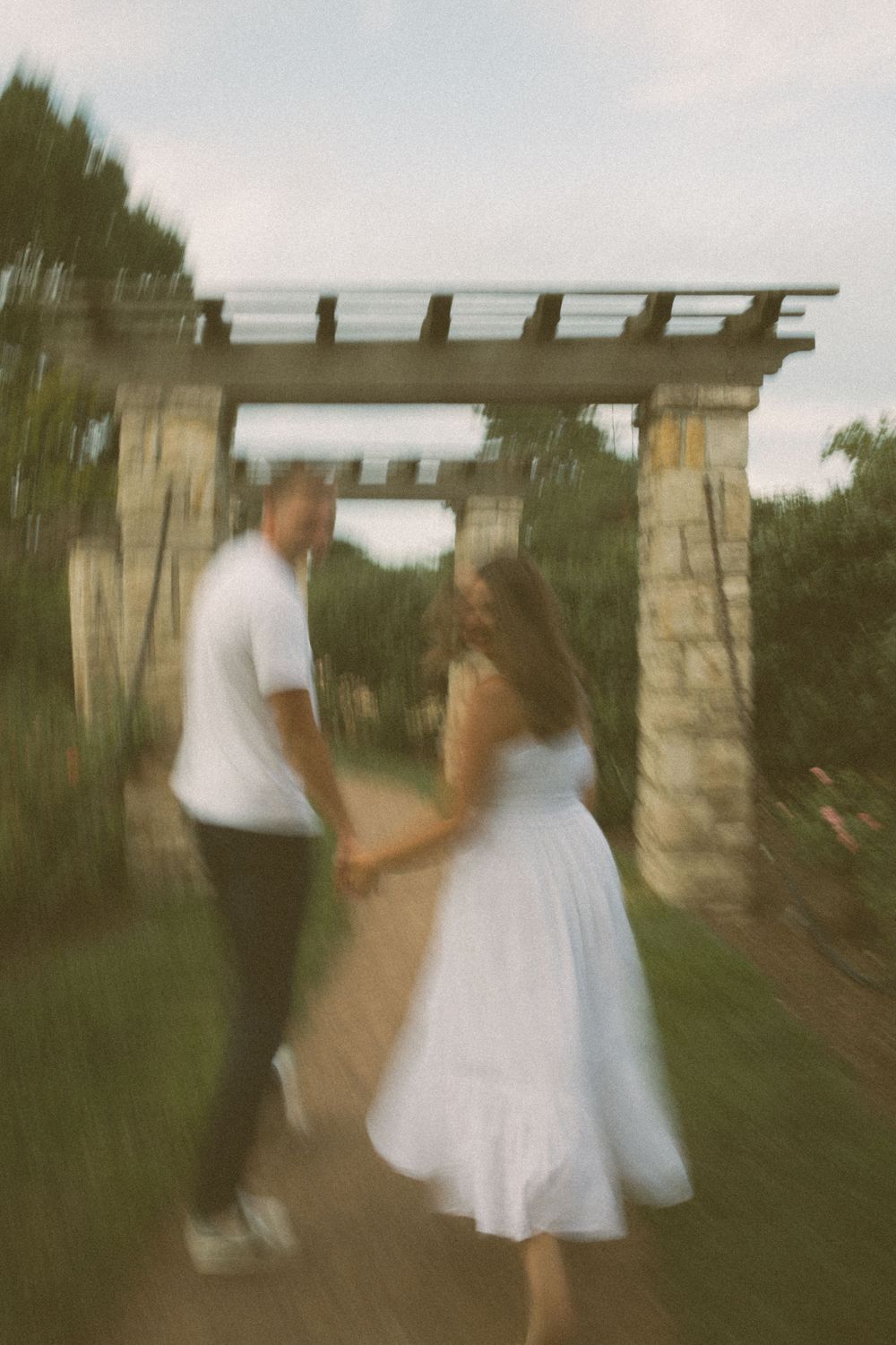 A dreamy, motion-blurred photo of a couple walking under a stone archway.