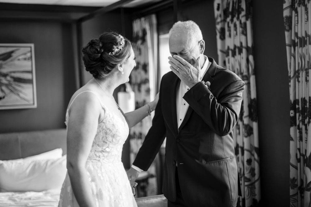 Black and white wedding photo capturing an emotional reaction in a hotel room.