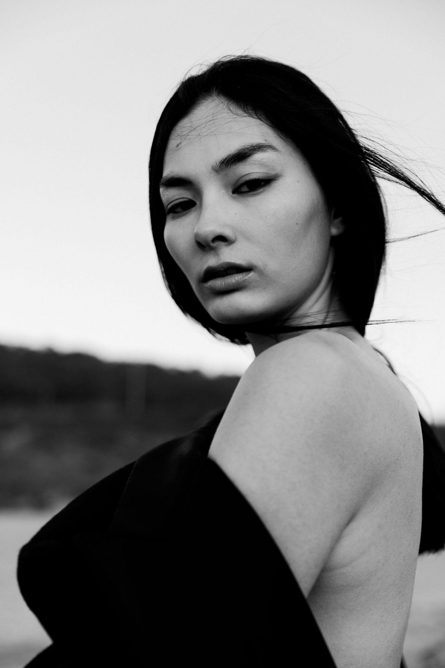 Black and white portrait in dramatic lighting with wind-swept hair.