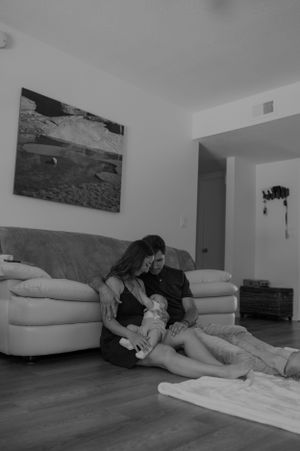 Black and white image of family relaxing together on living room floor.