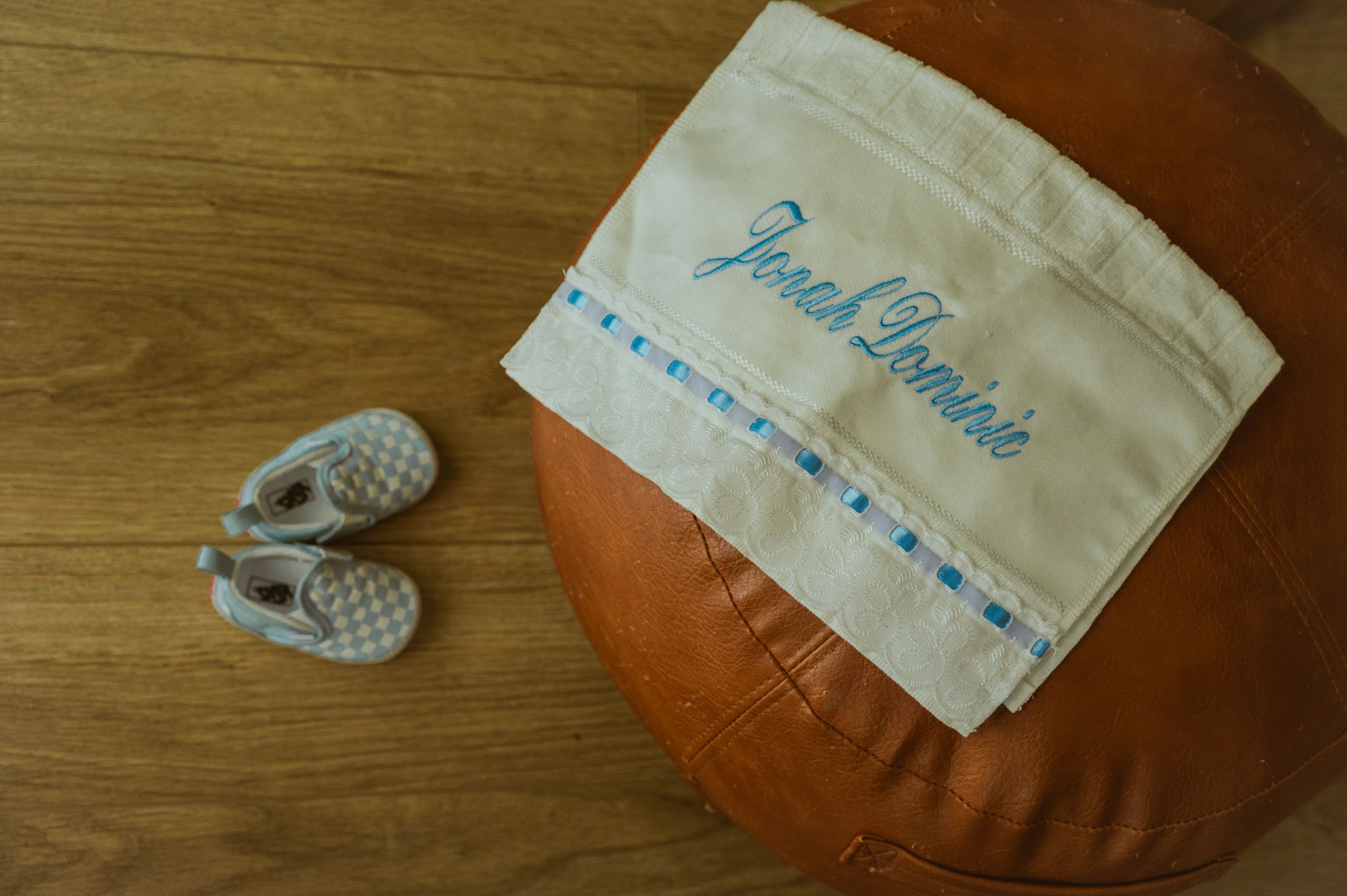 Close-up of baby items and embroidered fabric on wooden surface.