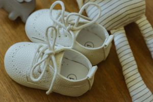 White baby shoes lined up on wooden floor.