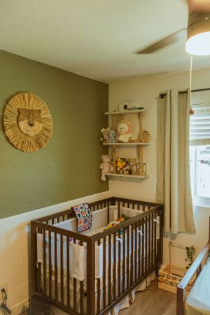 Nursery room with dark wood crib, decorative wall clock, and neutral decor.