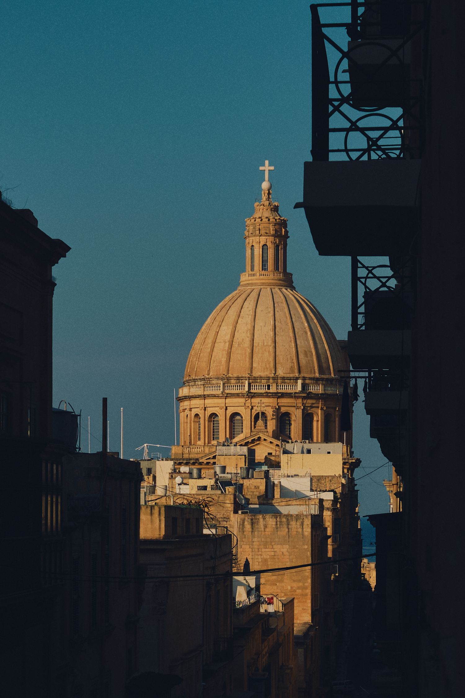 Majestic dome of Carmelite Church photographed between buildings during sunset in Valletta.