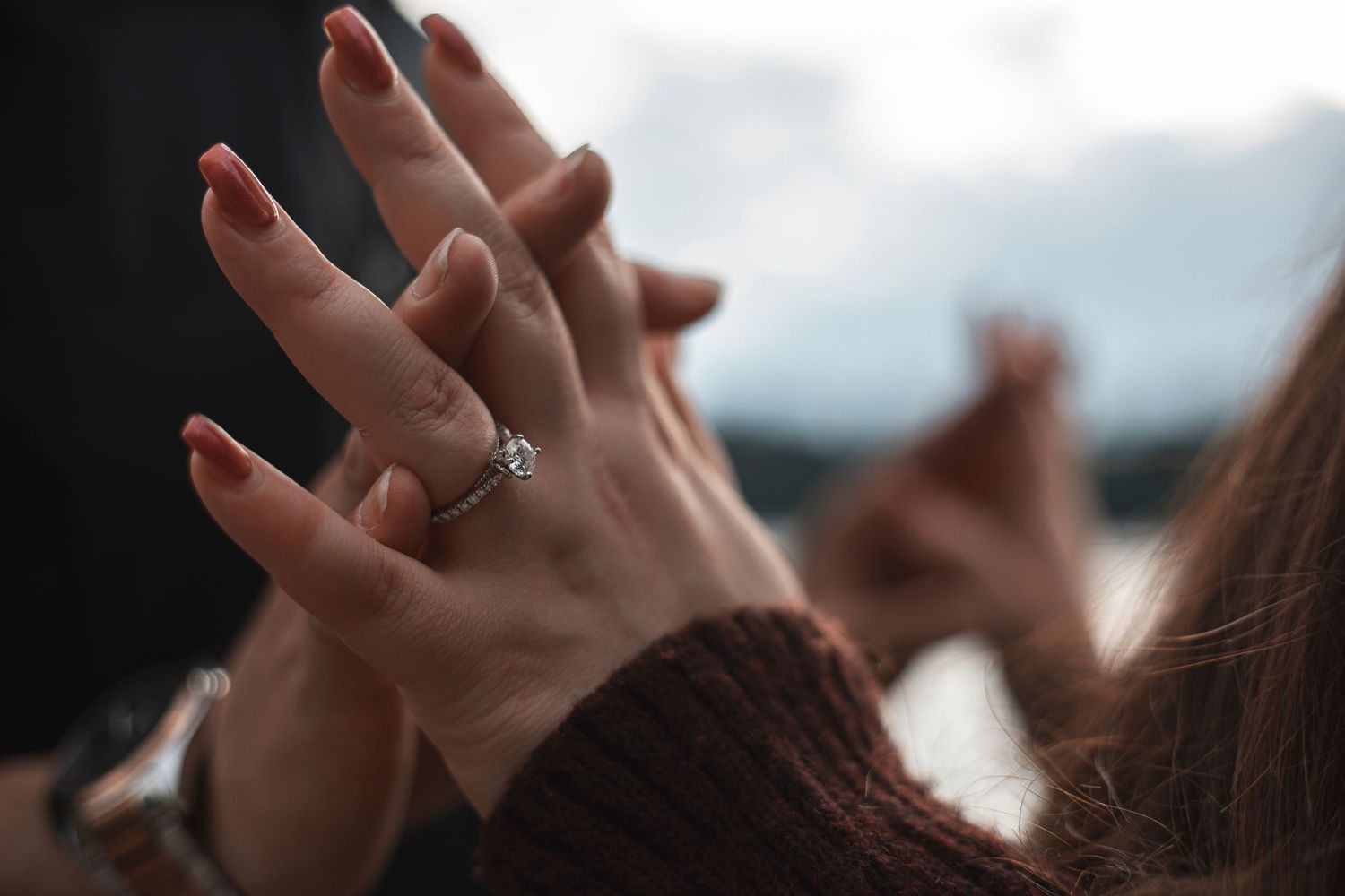 Wedding guests raise their hands in celebration during an outdoor ceremony.