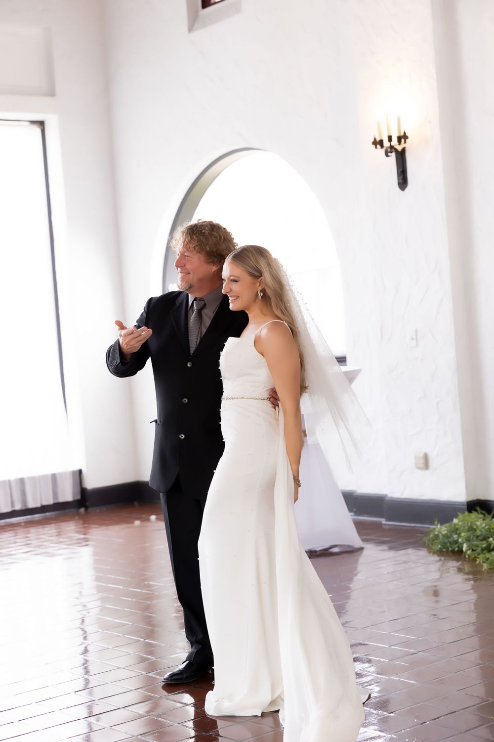 Elegant wedding portrait under an arched doorway on polished terra cotta floors.