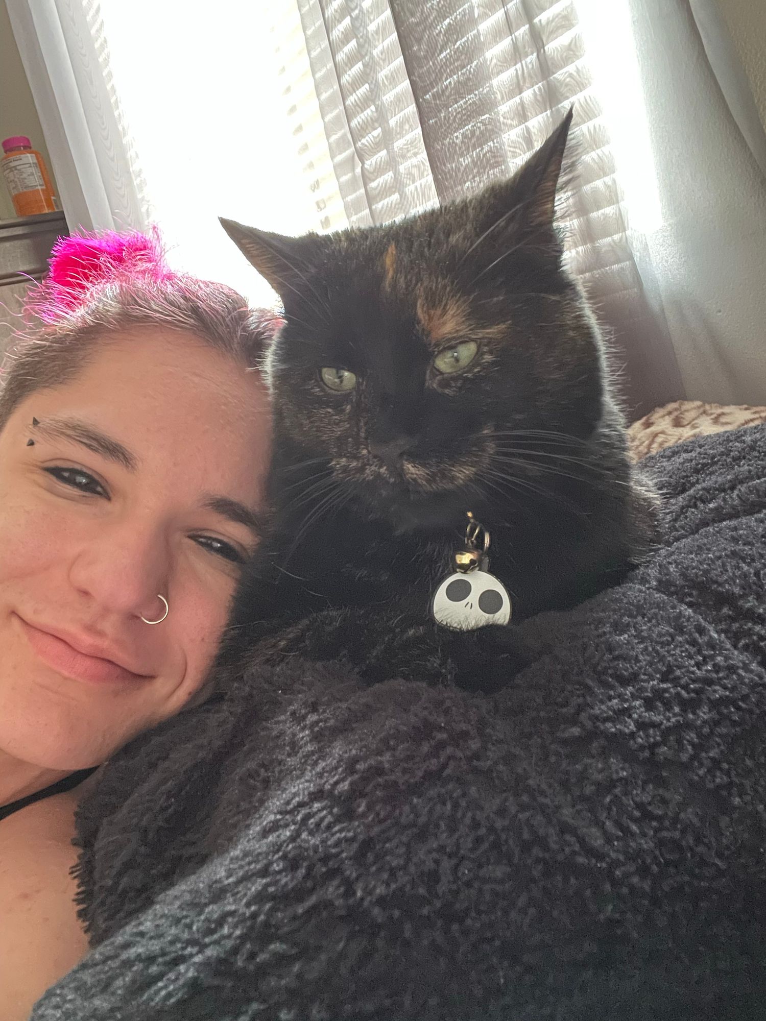 AJ smiling and laying next to their cat, Scarlet