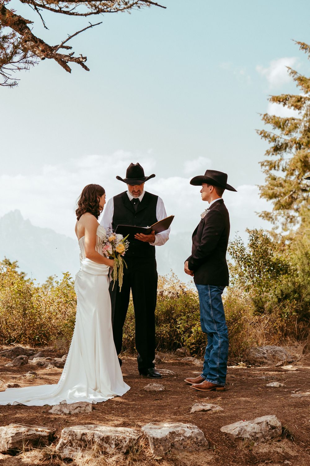 romantic western wedding portrait of a bride and groom embracing at sunset in the mountains