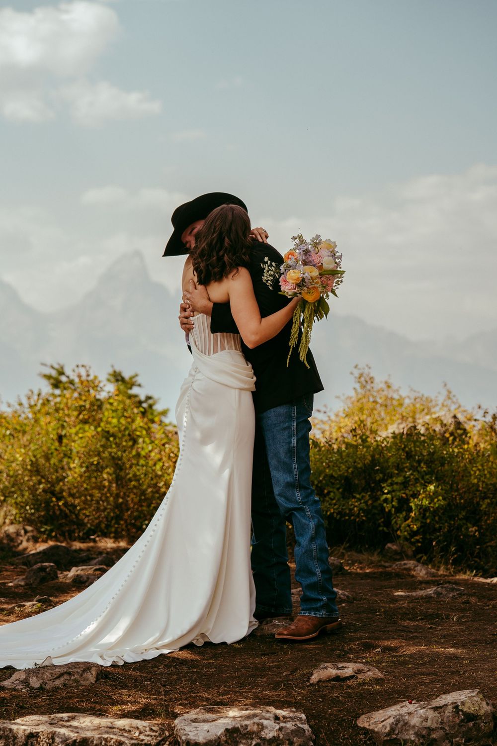 romantic western wedding portrait of a bride and groom embracing at sunset in the mountains