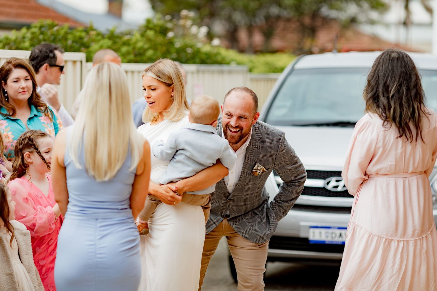A joyful group gathers outside in summer attire, sharing laughter and celebration.