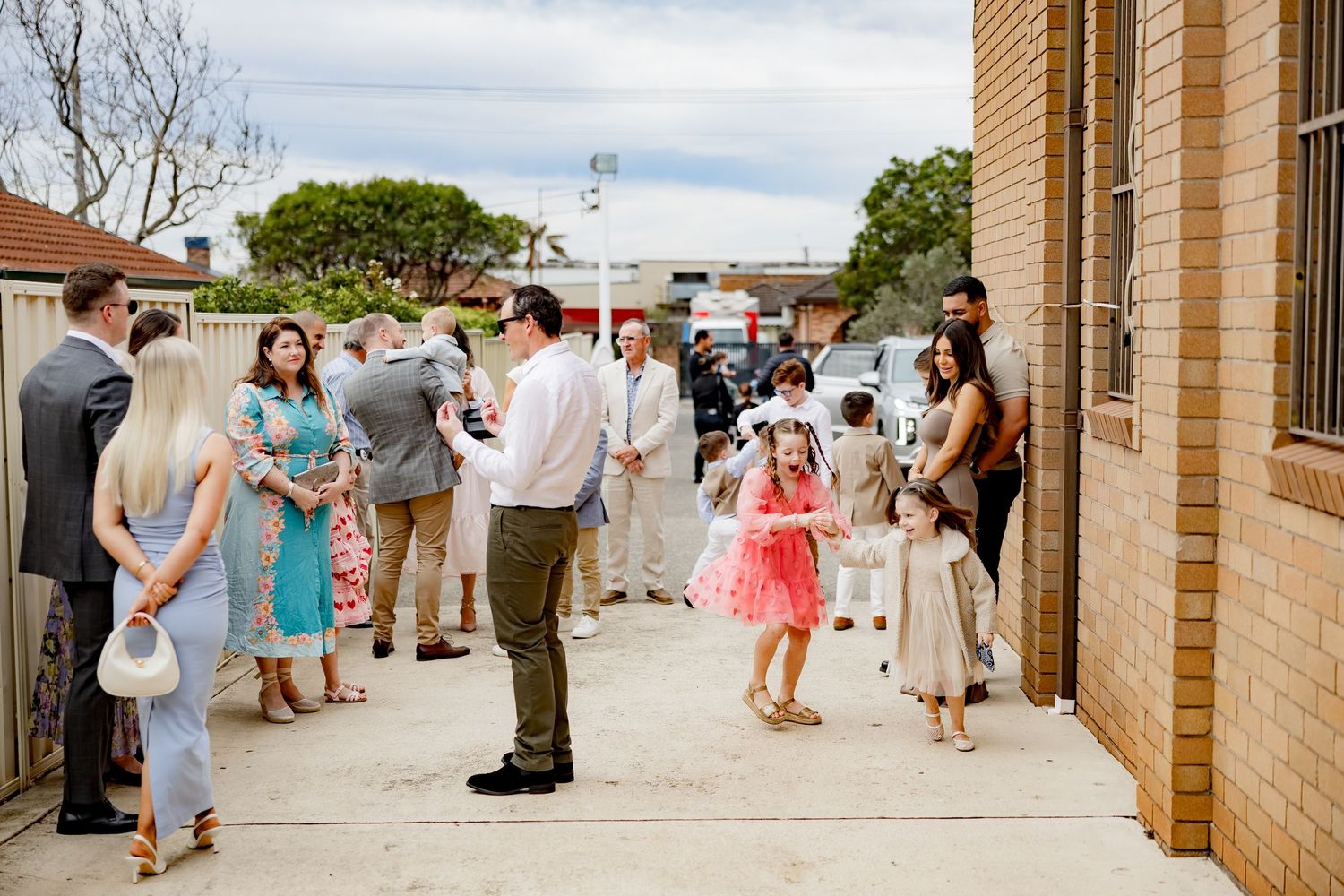People gather outside a brick church building for a celebratory event.