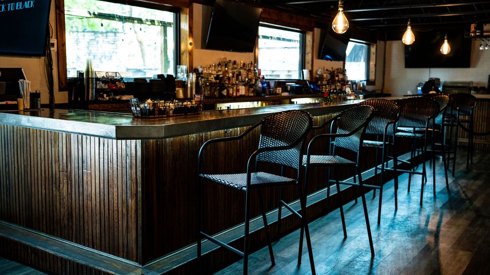 A panoramic view of a dimly lit restaurant interior with wooden furnishings and pendant lighting creating an intimate atmosphere.
