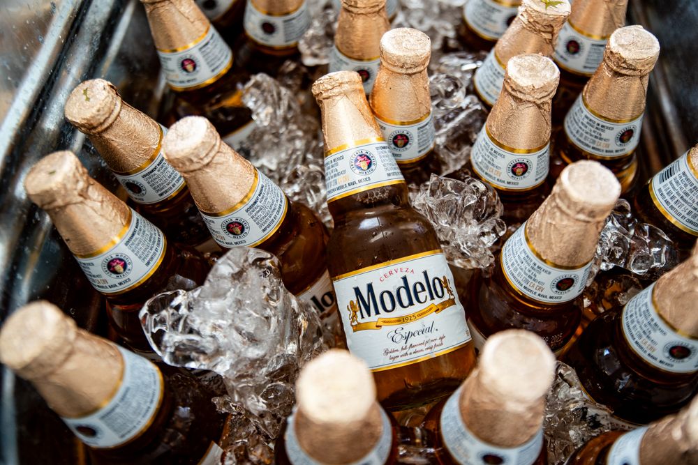 Chilled bottles of Modelo beer nestled in ice at a bar or party setting.