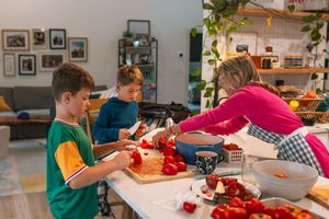 Students work diligently on craft projects at tables with red and white materials in a classroom setting.