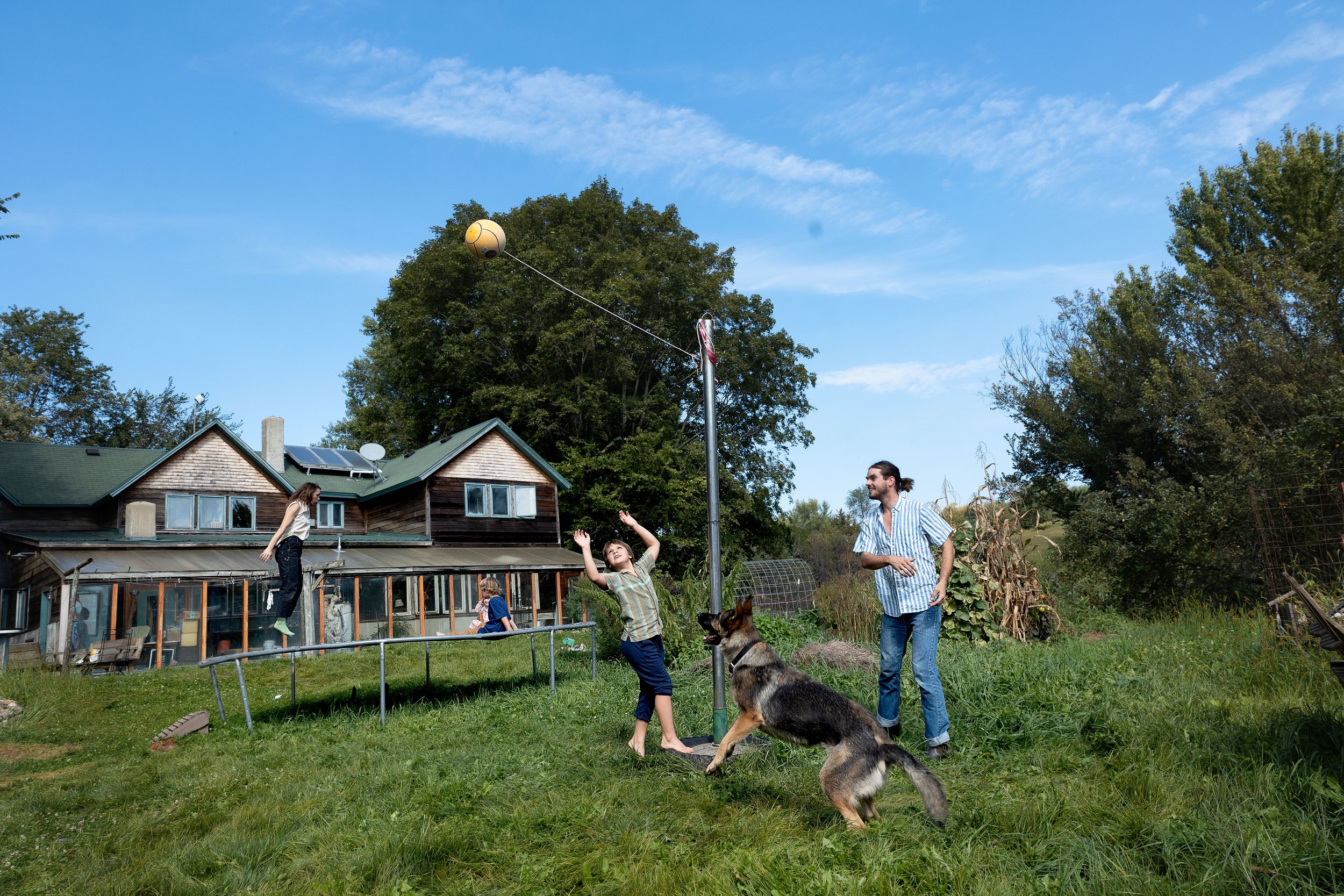 A sequence of photos showing someone doing a backflip on a grassy hillside in front of a house.