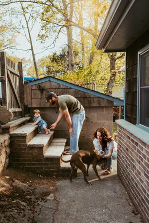 A series of photos showing people working together to build a garden retaining wall with concrete blocks in a backyard setting.