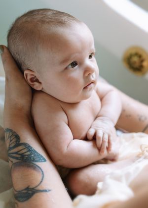 Close-up series of a newborn baby lying on soft white bedding while being photographed from different angles.