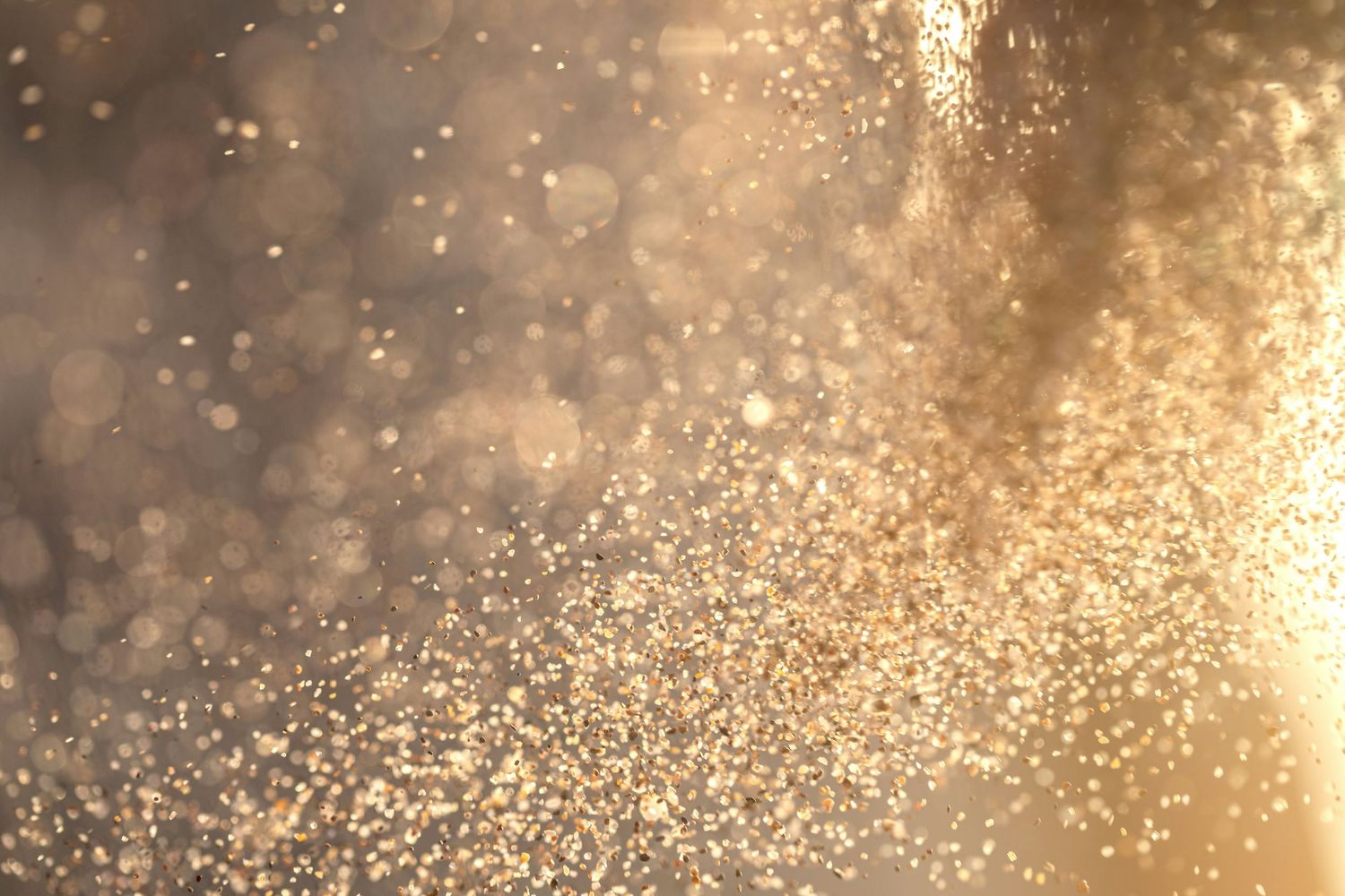 Golden water droplets and sparkles glisten in sunlight creating a magical bokeh effect.