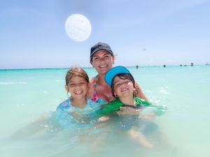 People enjoying the crystal clear turquoise waters at a tropical beach on a sunny day.