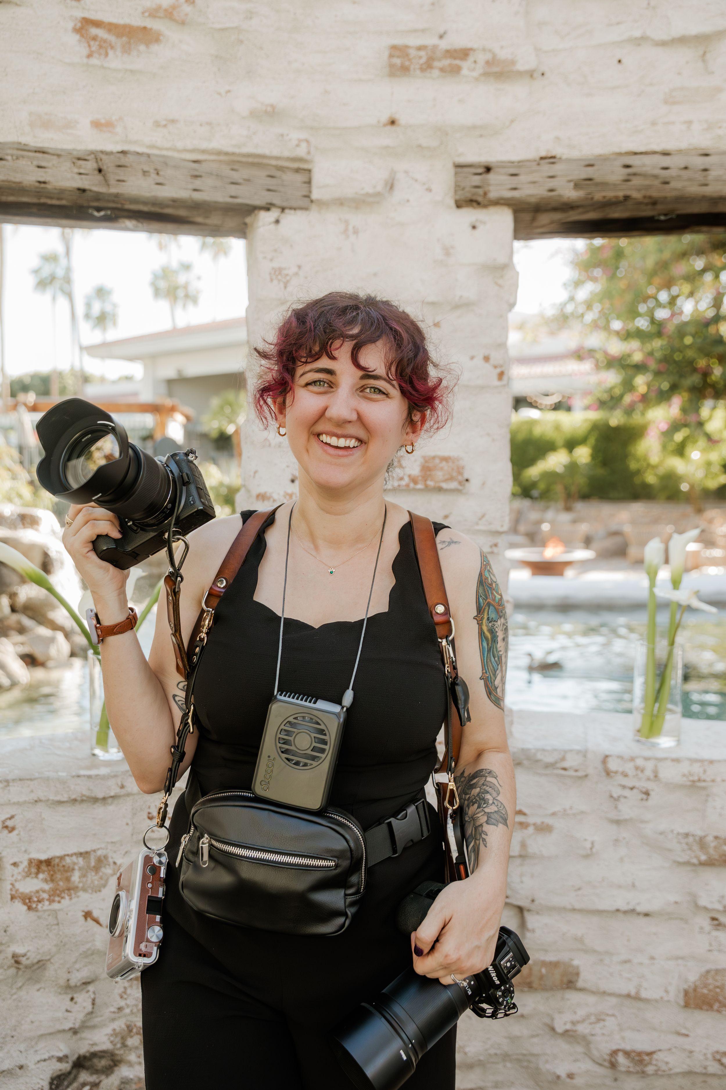Photographer with camera and decorative strap in outdoor setting.