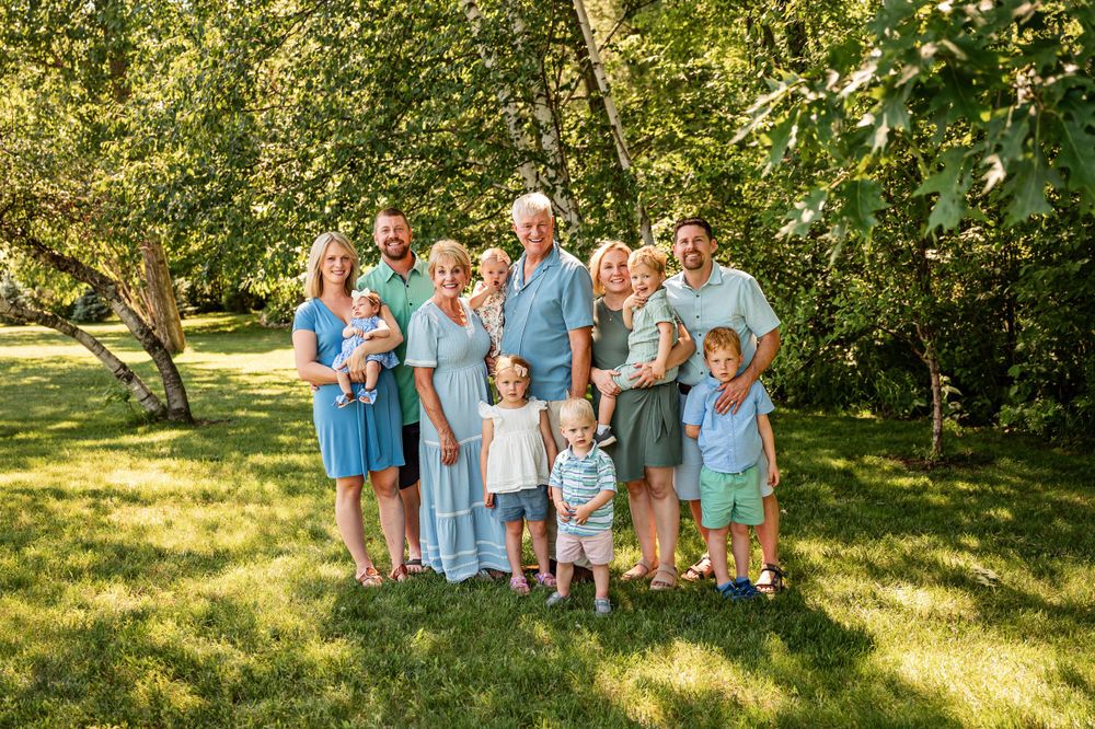 Extended family gathered for outdoor portrait wearing coordinated blue outfits.