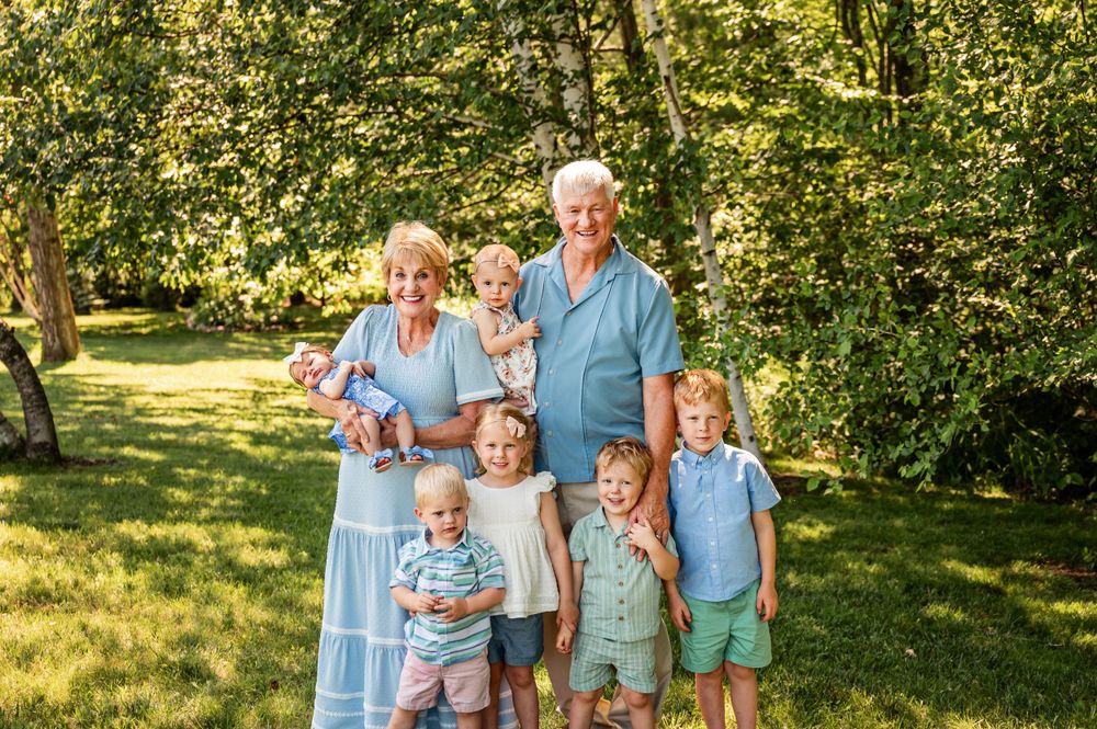 Multi-generational family poses for portrait in sunny garden setting.