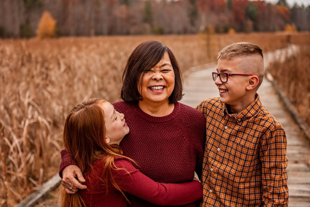 Cheerful autumn portrait of three people laughing together on wooden walkway.