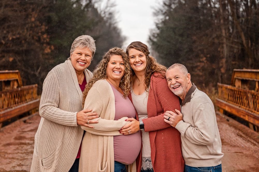 Happy group embracing and laughing together on wooden bridge during fall photoshoot.