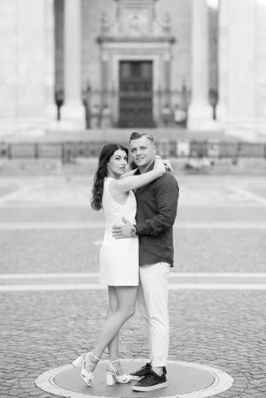 Black and white portrait of a couple embracing tenderly in front of a neoclassical building.