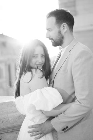 Black and white portrait of couple embracing in bright sunlight during romantic European engagement session.