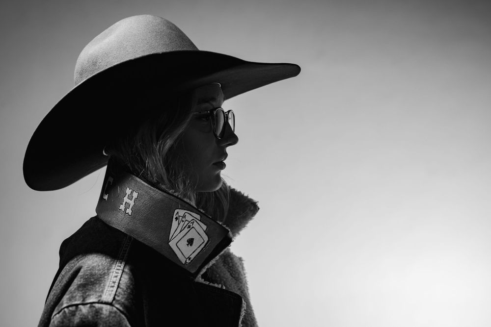 Black-and-white fine art portrait of a young woman in a cowboy hat during a studio session in Mountain Home, Arkansas