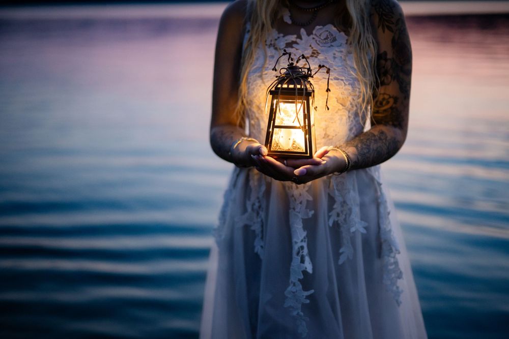 Fine art portrait of a woman in a white dress holding a lantern in the water at dusk in Arkansas