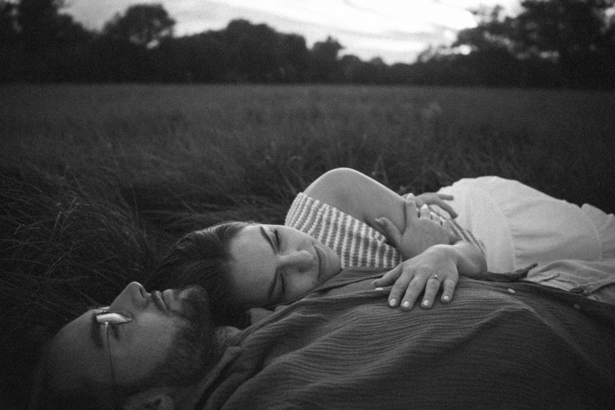 A series of black and white photographs showing someone lying down in different positions on a grassy surface.
