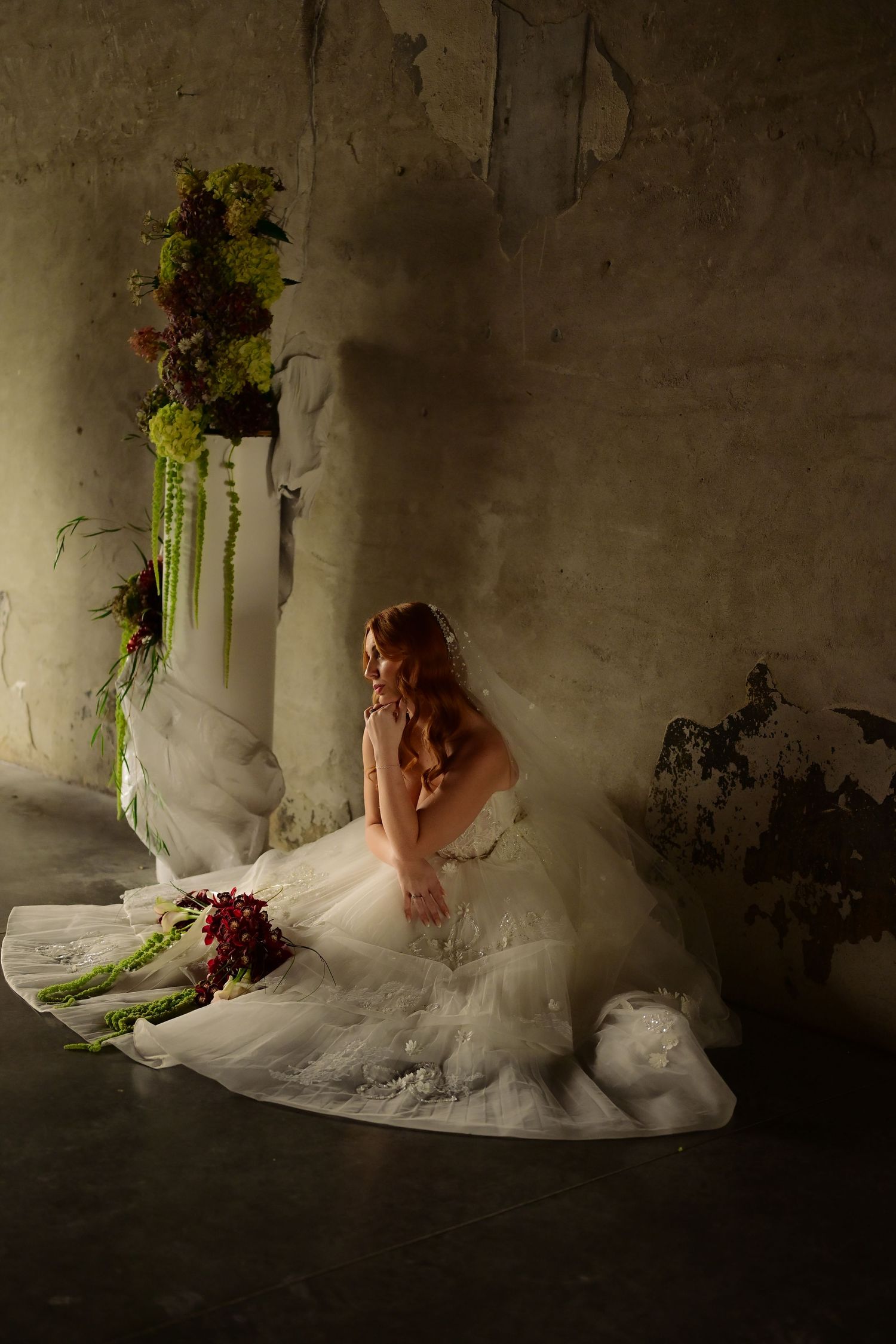 A wedding dress flows elegantly in motion against a dark moody background with dramatic lighting and floral accents.
