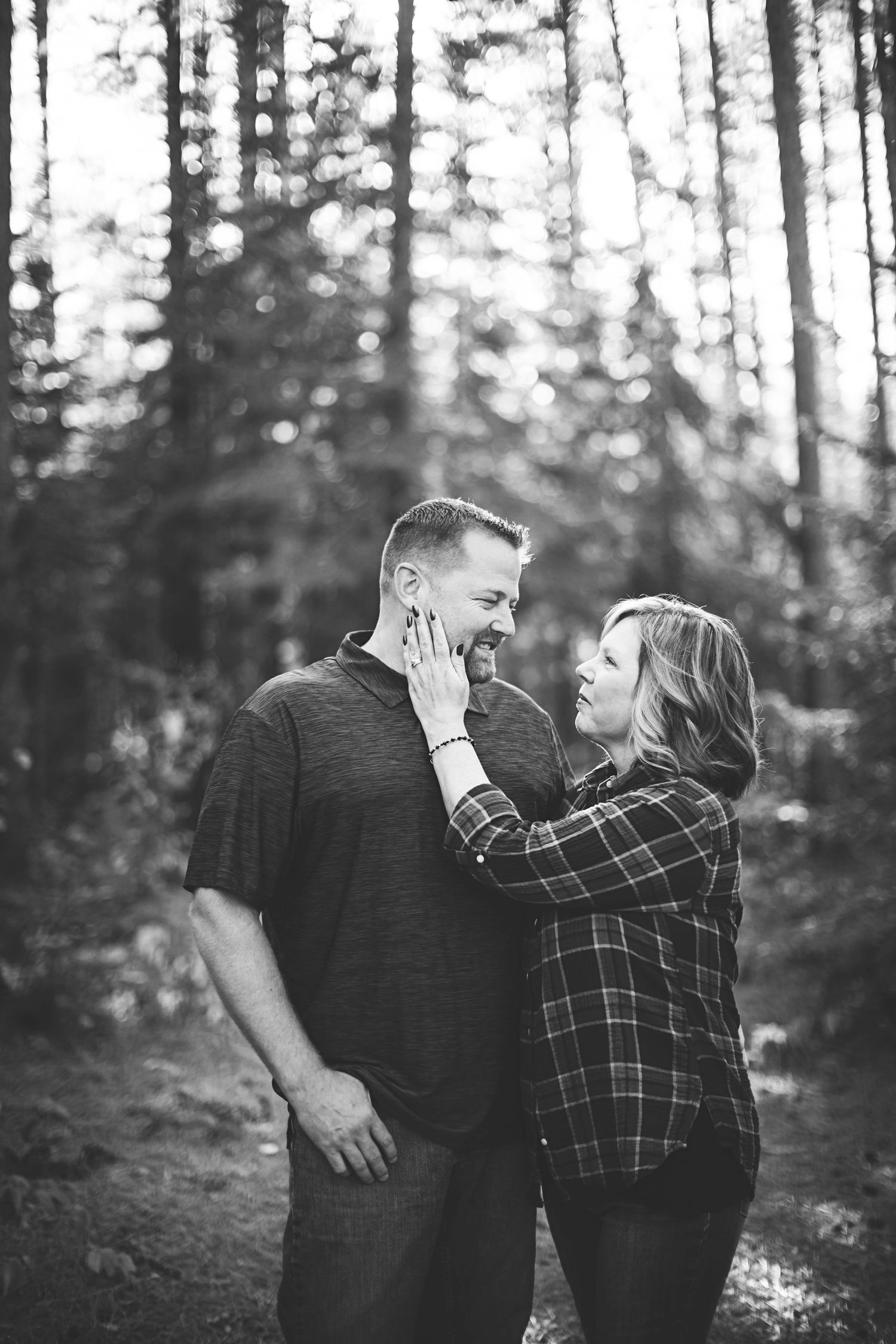 Intimate black and white portrait of couple in plaid shirts embracing in forest setting. Amnicon Falls Wisconsin Photography