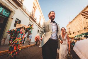 Dancing guests celebrate joyfully during a destination wedding at a rustic Mediterranean venue in warm sunlight.